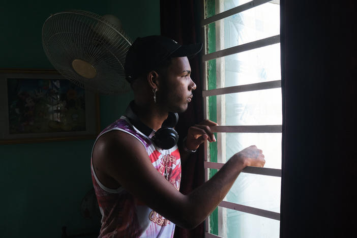 Gabriel Berrio Fabré, 18, looks out the window of his room in Los Pocitos, Havana. He is a visual artist, and like most of his friends, he wants to leave Cuba once he finishes his studies.