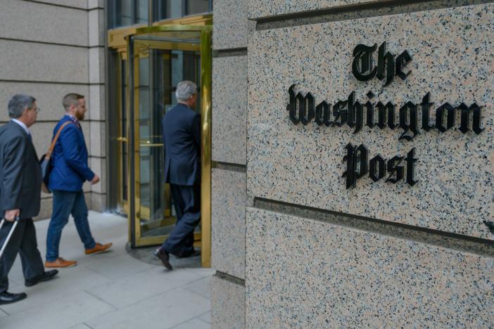 People enter The Washington Post's headquarters. The newspaper is cutting nearly 10% of its jobs through voluntary buyouts.