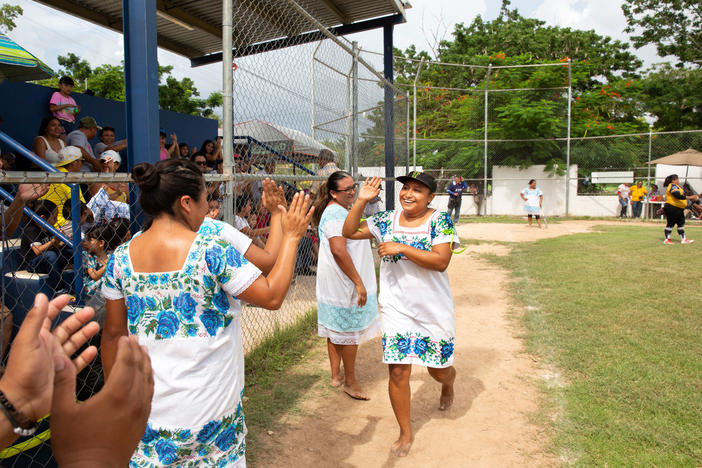 Sitlali Yovana Poot Dzib, 20 (left), captain of The Amazonas of Yaxunah, high fives her teammates after a home run in a game played on Sept. 10. The indigenous women on the team live in the small Maya community of Yaxunah in Mexico's Yucatán Peninsula. They wear traditional Maya garb when they play — and eschew shoes.