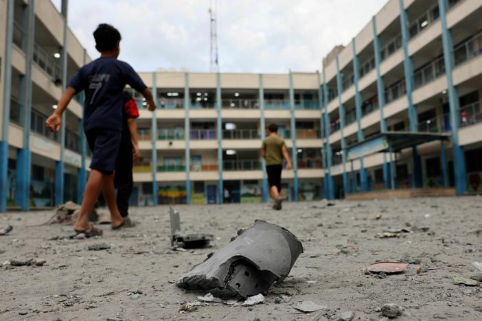 Palestinian children walk past debris in the courtyard of a school run by the United Nations Relief and Works Agency for Palestine refugees following Israeli airstrikes targeting Gaza City on Monday.