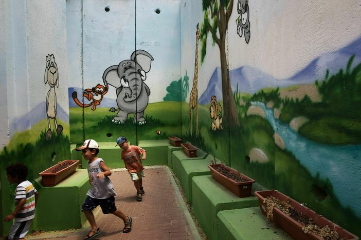 Children play at a kindergarten surrounded by decorated concrete blast walls designed to protect from rocket and mortar fire in 2015 in the southern Israeli Kibbutz of Nahal Oz near the border with the Gaza Strip.