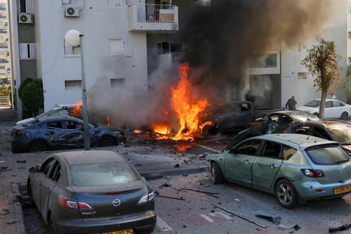 A member of the Israeli security forces stands near burning cars following a rocket attack from the Gaza Strip in Ashkelon, southern Israel, on Oct. 7.
