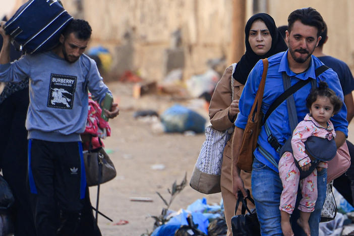 Palestinians with their belongings flee from their homes following Israeli airstrikes in Gaza City on Friday.