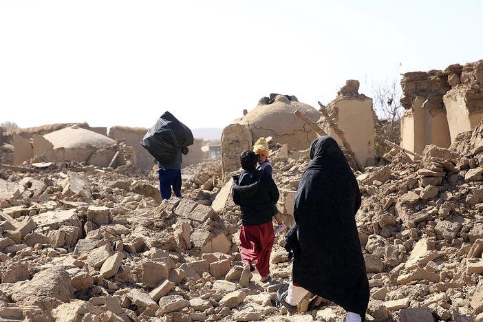 An Afghan woman walks with her children amid debris after a powerful earthquake struck Herat province in western Afghanistan on Sunday, Oct. 15, 2023.