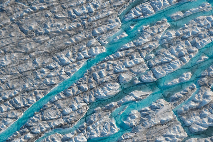 Rivers of meltwater carve into the Greenland ice sheet. Melting at the ice sheet's surface can spur more melt, creating a dangerous feedback loop.