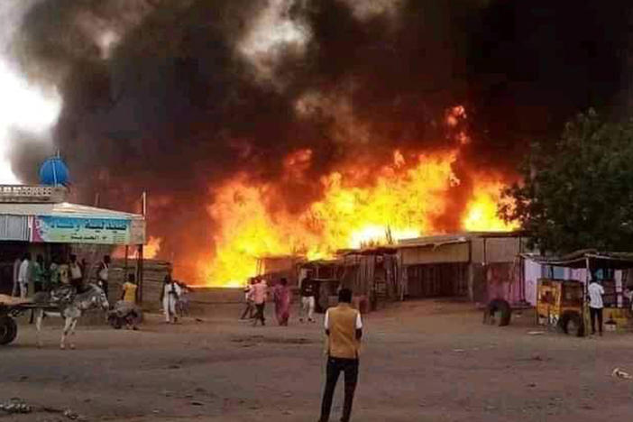 A man stands by as a fire rages in a livestock market area in al-Fasher, the capital of Sudan's North Darfur state, on Sept. 1, in the aftermath of bombardment by the paramilitary Rapid Support Forces (RSF).