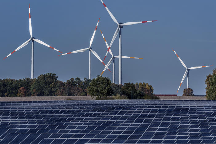 Wind turbines turn behind a solar farm in Rapshagen, Germany in 2021. The International Energy Agency projects demand for fossil fuels will peak before 2030 as renewable energy continues to grow.