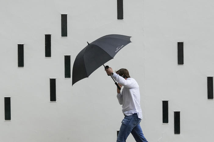 A man walks in the rain along a street in Austin, Texas, Nov. 11, 2022.