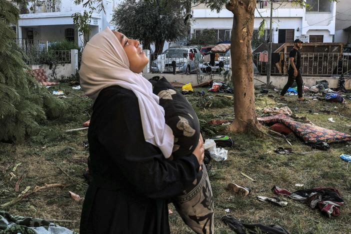 A woman holds a pillow near the Al Ahli Arab Hospital in Gaza City, the site of a blast that killed hundreds on October 17. In the aftermath, Hamas and Israel traded blame.