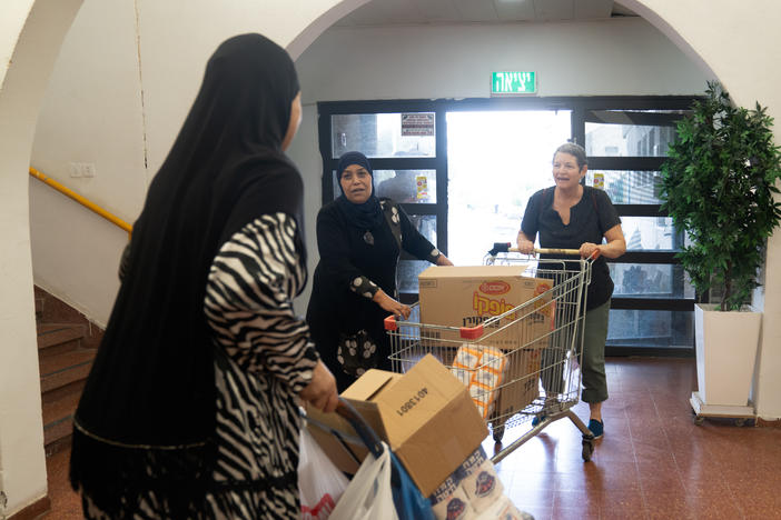 Smadar Tzimmerman (right) helps push a cart with donations into the community center in Lod, Israel.