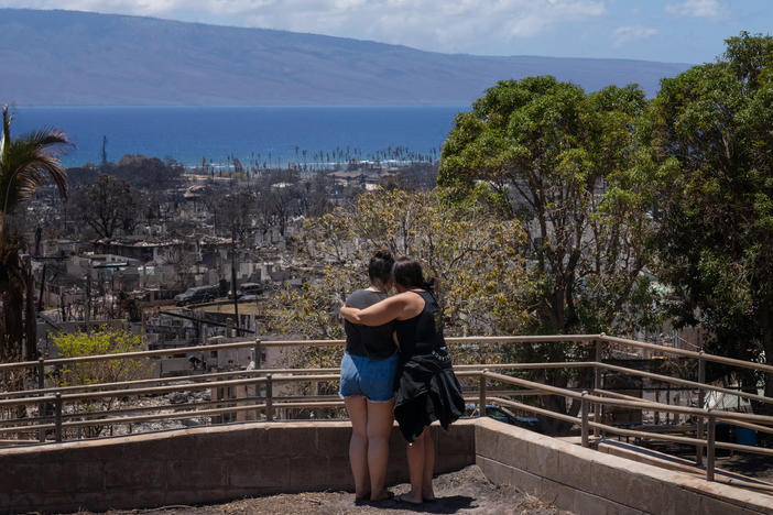 Two women embrace and cry as they look out over a burned area in Lahaina, Hawaii in August 2023. A new survey finds most Americans expect the impacts of climate change to worsen in the next 30 years, as climate scientists warn.