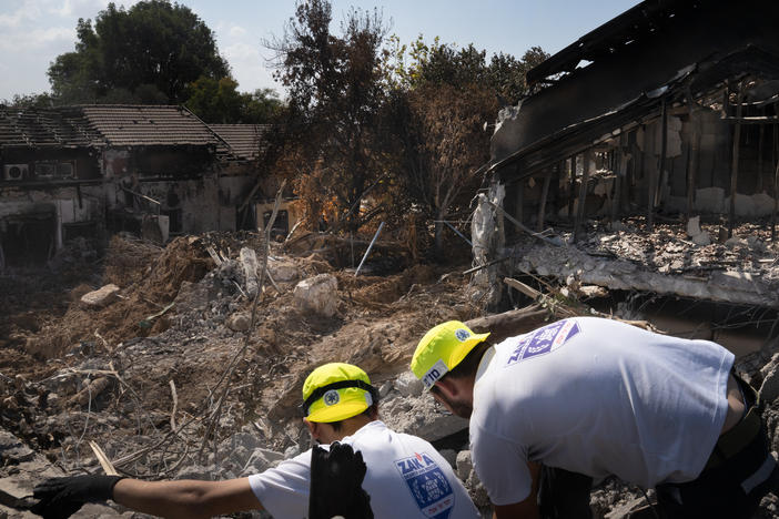 Men working with a search and recovery team from the organization ZAKA look for human remains in Kibbutz Be'eri.