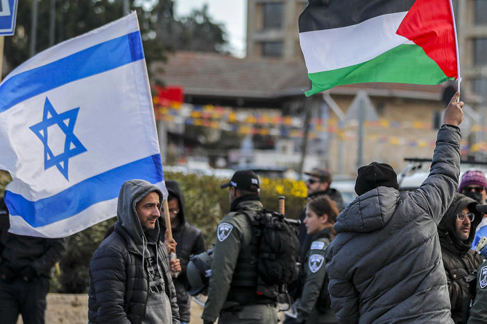 An Israeli settler stands with an Israeli flag before a man holding up a Palestinian flag during a demonstration in the East Jerusalem neighborhood of Sheikh Jarrah in February 2022.