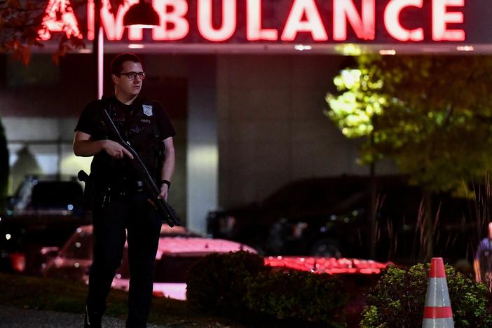 An armed police officer guards the ambulance entrance to the Central Maine Medical Center in Lewiston, Maine, early on Oct. 26, 2023. A massive manhunt was under way for 40-year-old Robert Card, who officials identified as a person of interest.