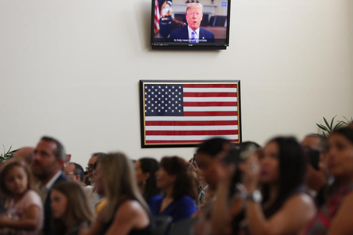 A recorded video message by then-President Donald Trump plays at a 2019 naturalization ceremony for new U.S. citizens at the U.S. Citizenship and Immigration Services field office in Miami.