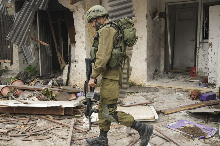 An Israeli soldier walks past a house damaged during the Hamas attack in Kibbutz Kfar Azza, Israel, on Friday. The Kibbutz was attacked on Oct. 7.