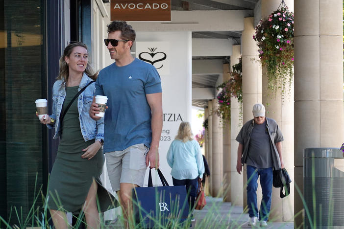 A shopper carries a shopping bag while walking through an outdoor shopping center in Corte Madera, Calif., on Oct. 17. Strong consumer spending is helping to power the economy — but it may not last.