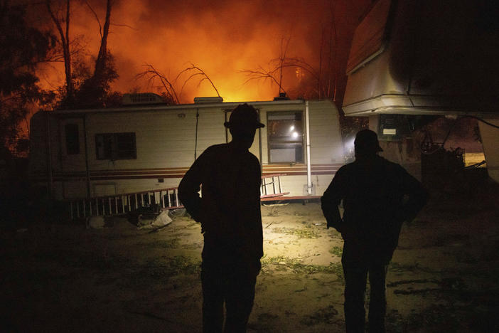 A firefighter and resident converse on how to protect his possessions as a wildfire called the Highland Fire burns in Aguanga, Calif., on Monday.