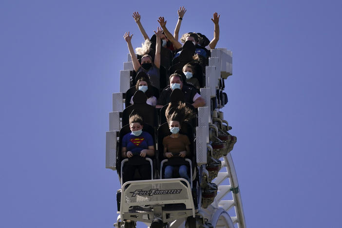 Visitors wearing masks ride on a roller coaster at Six Flags Magic Mountain on its first day of reopening to members and pass holders in Valencia, Calif., on April 1, 2021.