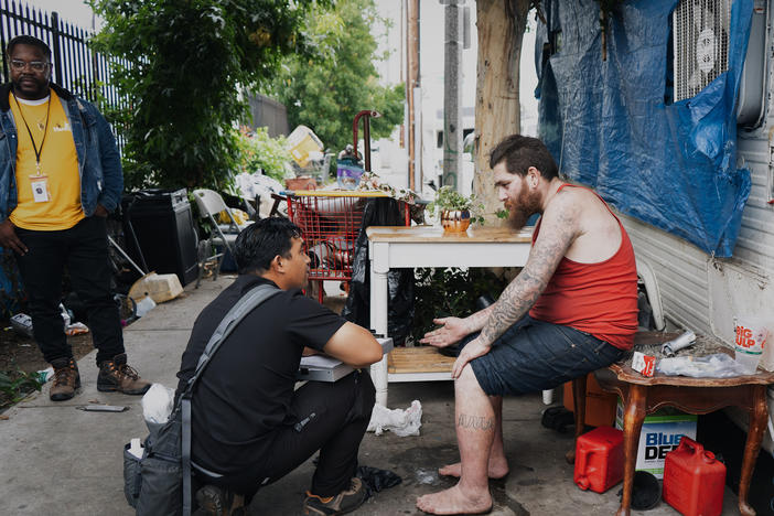 Anthony Velbis, a nurse with the homeless service agency HOPICS, checks up on Anthony Boladeres outside the RV where he's living in South Los Angeles. "It's nice being able to meet the client where they're at," Velbis says.