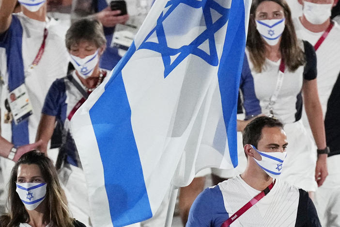 Hanna Minenko and Yakov Toumarkin, of Israel, carry their country's flag during the opening ceremony in the Olympic Stadium at the 2020 Summer Olympics in Tokyo.