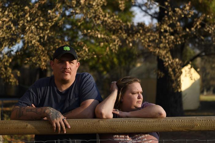 Army veteran Ray Queen stands with his wife, Rebecca Queen, outside their home in Bartlesville, Okla. An NPR investigation has found that thousands of U.S. military service members and veterans, including the Queen family, are at risk of losing their homes through no fault of their own.