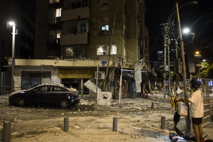 A man passes the scene where a rocket fired from Gaza strip hit a building on Oct. 7, 2023 in Tel Aviv, Israel. Israeli officials revised down the estimated number of people killed in the Oct. 7 attacks to 1,200 from 1,400 on Friday.