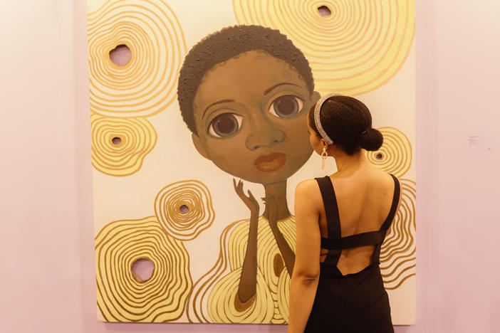 An attendee views one of rising artist Adulphina Imuede's dreamlike illustrations at ART X.