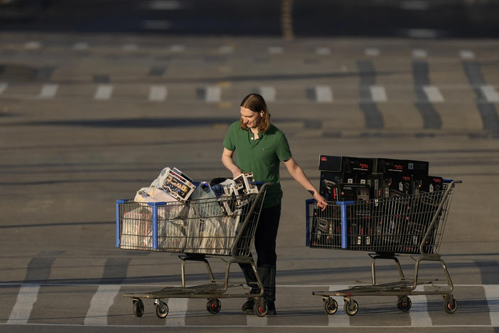 A shopper pushes two carts during last year's Black Friday sale at a Best Buy store in Overland Park, Kan.