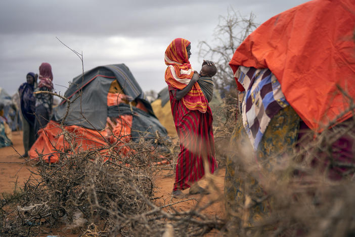 A woman breastfeeds her child at a camp for displaced people in Somalia, where climate change is fueling severe drought.