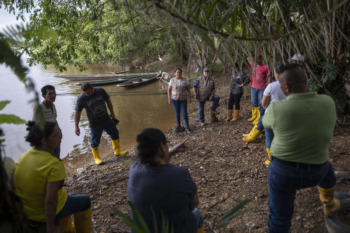 Yuly Velásquez (center in tan vest) president of a local fishers association and a clean-water advocate, meets with its members on a tributary of the Magdalena River. She has been attacked three times in the past two years for her environmental work.