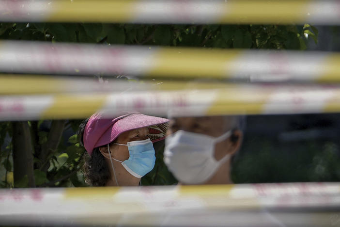 Residents wearing face masks line up behind barricaded tapes for COVID mass testing near a residential area on May 15, 2022, in Beijing. The World Health Organization says it's made an official request to China for information about a potentially worrying spike in respiratory illnesses and clusters of pneumonia in children.