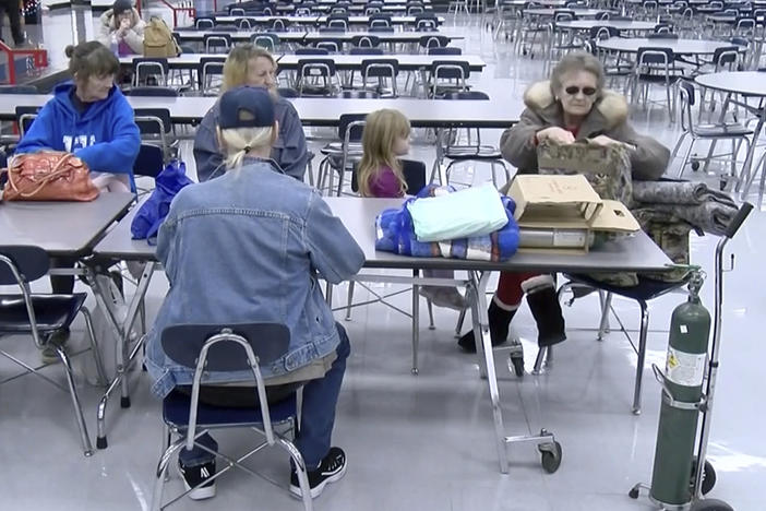This image provided by WTVQ and taken from video shows people sitting at a table at Rockcastle Middle School, an evacuation center in Mt. Vernon, Ky., on Wednesday. People were evacuated after a CSX train derailed near Livingston, a town of about 200 people in Rockcastle County. CSX says two of the 16 cars that derailed carried molten sulfur, which caught fire after the cars were breached.