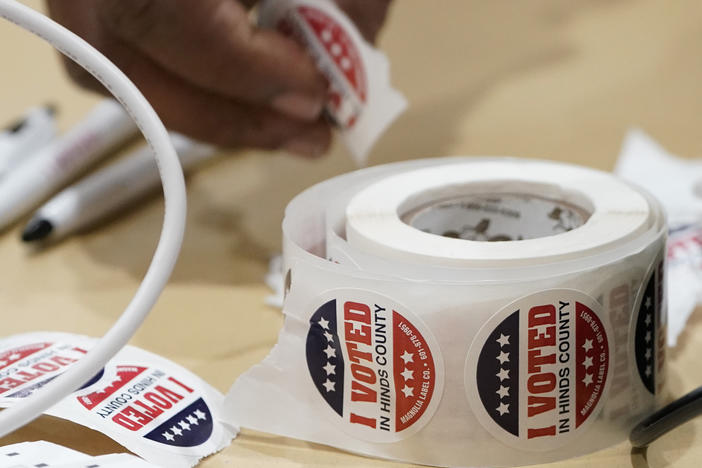 A precinct worker reaches for more "I Voted" stickers on Nov. 7 in Jackson, Miss. A few polling places in Jackson's Hinds County saw ballot shortages during this year's statewide general election, frustrating voters.