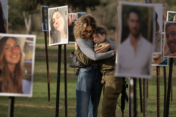 Sigal Manzuri, whose daughters Norelle and Roya were killed in the Hamas-led attack on the Nova music festival on Oct. 7, embraces one of their friends. Surrounding them are photos of people killed and taken hostage by Hamas militants, displayed at the site as DJs spin music to commemorate victims, near Kibbutz Re'im, Tuesday.