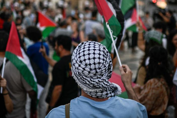 A protestor wearing a keffiyeh waves a Palestinian flag during a rally in support of Palestinians in Lisbon in October.