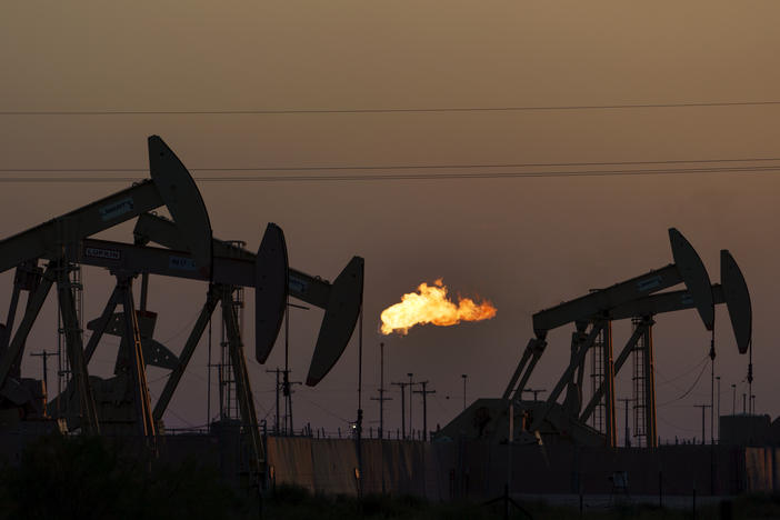 A flare burns off methane and other hydrocarbons as oil pumpjacks operate in the Permian Basin in Midland, Texas, Oct. 12, 2021.