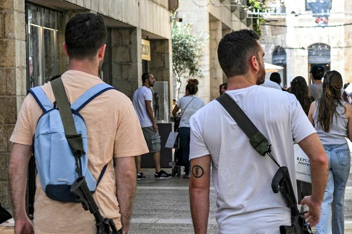Israeli men, armed with U.S.-made M16 automatic assault rifles, walk in a shopping center in Jerusalem on Oct. 25, amid the ongoing battles in the Gaza Strip between Israel and Hamas.