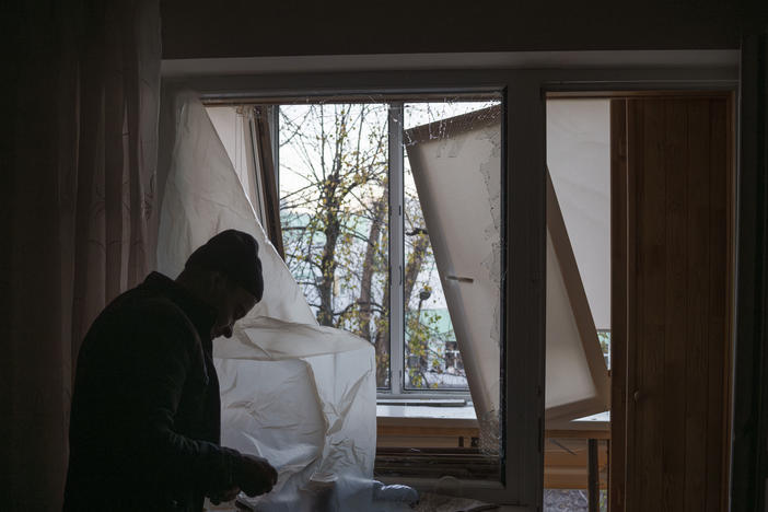 A man uses plastic to cover a broken window in his apartment following a Russian drone attack in Kyiv, Ukraine, on Nov. 25.