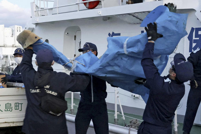 Members of the Japanese Coast Guard carry debris believed to be from the crashed U.S. military Osprey aircraft at a port in Yakushima, southern Japan, on Monday.