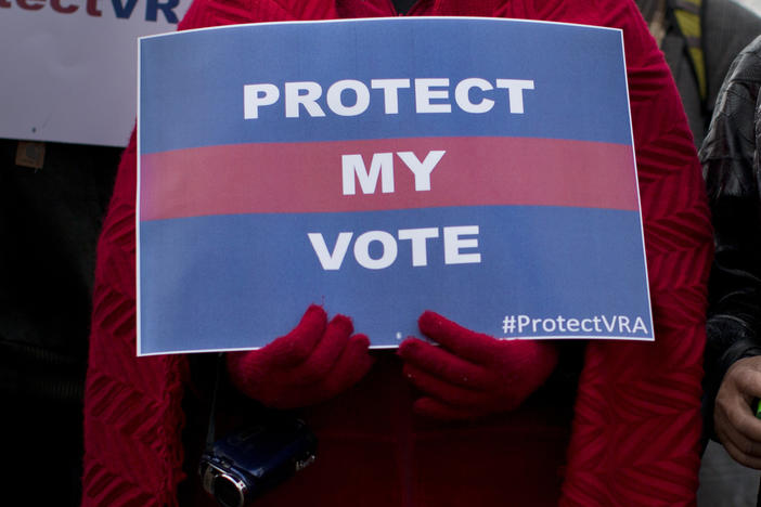 People carrying signs in support of the Voting Rights Act line up outside the U.S. Supreme Court in Washington, D.C., in 2013.