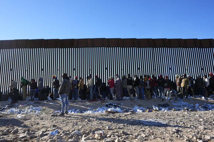 Hundreds of migrants gather along the border wall Tuesday, Dec. 5, 2023, in Lukeville, Ariz. The U.S. Border Patrol says it is overwhelmed by a shift in human smuggling routes.