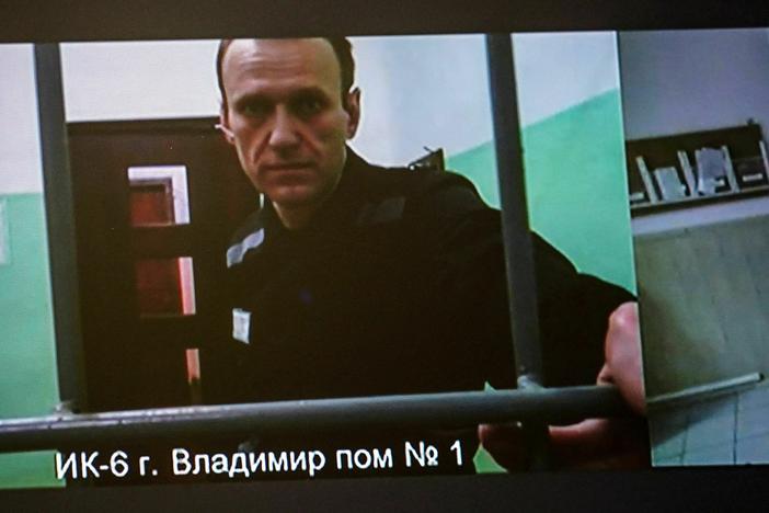 A screen shows jailed Kremlin critic Alexei Navalny as he arrives to listen to a hearing on an appeal lodged against a court decision to jail him for 19 years in a maximum security prison on extremism-linked charges, at a court in Moscow on Sept. 26.