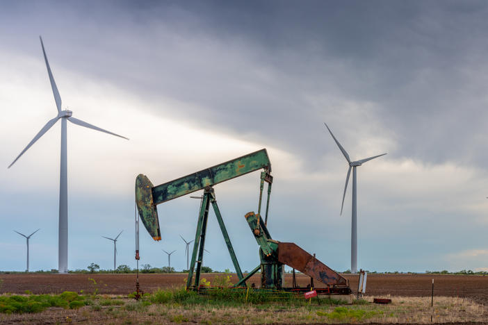 An oil pump jack stands near a field of wind turbines in Nolan, Texas, on Oct. 4. Oil companies are under pressure to pivot more swiftly toward renewable energy. Here's one reason why that's not happening so quickly: It's still incredibly lucrative to sell oil.