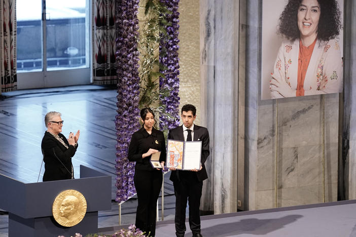 Nobel Committee chair Berit Reiss-Andersen (L) applauds as Kiana Rahmani and Ali Rahmani pose with the award on behalf of their mother during the 2023 Nobel Peace Prize ceremony at the Oslo City Hall on December 10, 2023.