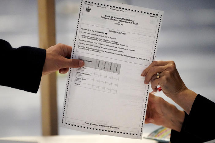 A clerk hands a ballot to a voter on Election Day, Nov. 8, 2022, in Lewiston, Maine. The state is one of 50 American voting jurisdictions to have moved to a ranked choice voting system, and more places may follow next year.