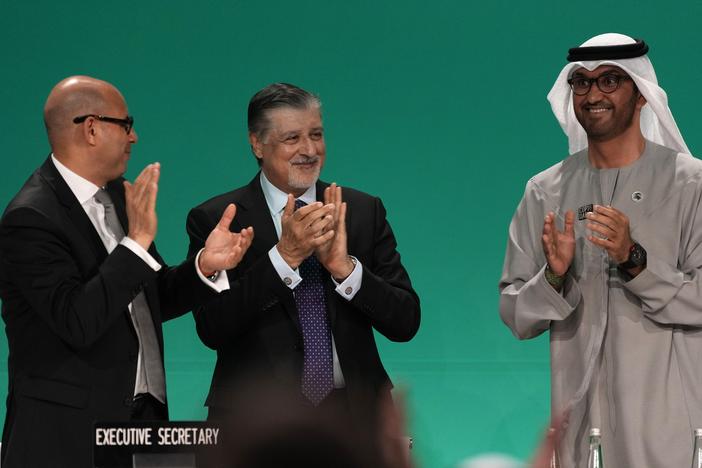 Sultan al-Jaber of the United Arab Emirates, right, celebrates the end of the COP28 climate meeting with United Nations Climate Chief Simon Stiell, left, and COP28 CEO Adnan Amin on Dec. 13, 2023, in Dubai. The final deal included a modest reference to transitioning away from fossil fuels, which scientists say is crucial to avoid catastrophic warming.