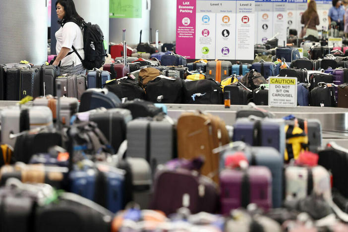A traveler looks for baggage amid rows of unclaimed luggage at Los Angeles International Airport in June.