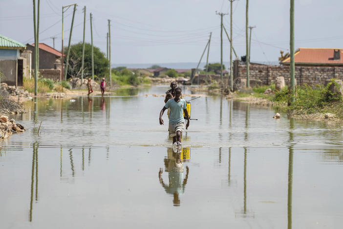 People wade through a section of a road destroyed by floods in Mandera County, Kenya, Wednesday.