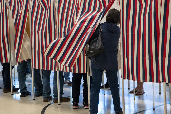 A voter enters a booth to fill out their ballot in Manchester, N.H., in 2022.